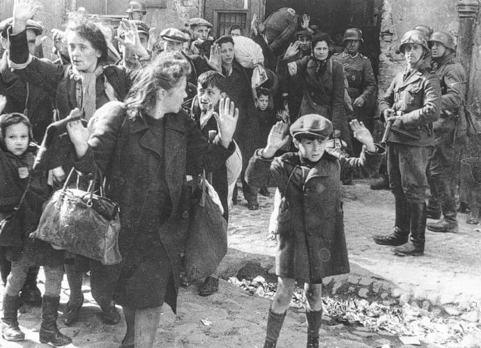 A group of Jews, including a small boy, is escorted from the Warsaw Ghetto by German soldiers on April 19, 1943. The picture formed part of a report from SS Gen. Stroop to his Commanding Officer, and was introduced as evidence to the War Crimes trials in Nuremberg in 1945. (AP Photo/B.I. Sanders)