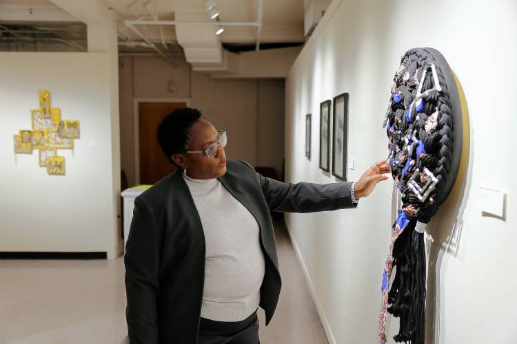 Curator and UMass art professor Juana Valdes, seen here with work by Chire “Vanta Black” Regans at “As We Move Forward,” says the UMass exhibit is designed to honor the legacy of Augusta Savage, the seminal Black sculptor who was born in Florida.