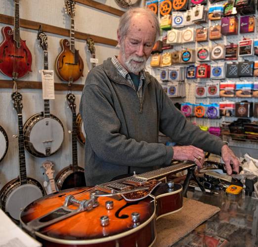 Tony Creamer, owner of the Fretted Instrument Workshop in Amherst, works on a repair at the shop on Friday afternoon. Creamer plans to shutter his business this spring after more than 50 years.