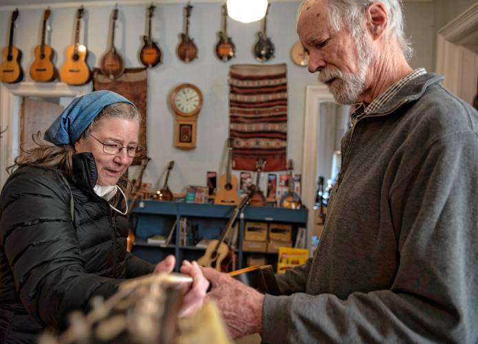 Tony Creamer, owner of the Fretted Instrument Workshop in Amherst, shows Robin Harrington the guitar he recently repaired for her at the shop on Friday afternoon.