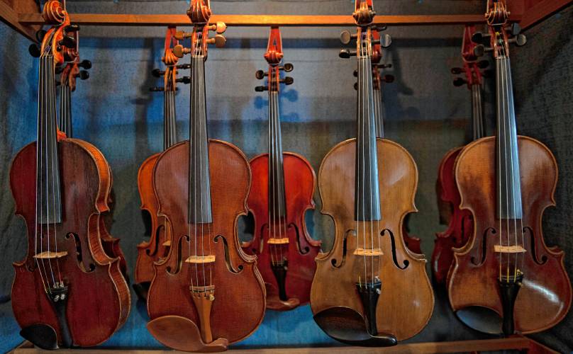 FAR LEFT: Violins hang from a rack at Fretted Instrument Workshop in Amherst, which will close on April 1.