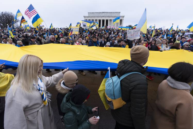 Ukrainians and their supporters carry a huge Ukrainian flag during a rally at the National Mall near the Lincoln Memorial in Washington, Saturday, Feb. 24, 2024. A new poll from The Associated Press-NORC Center for Public Affairs Research finds that U.S. adults have become fractured along party lines in their support for military aid for Ukraine.